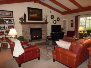 living room with leather couches, stone fireplace and beamed ceiling