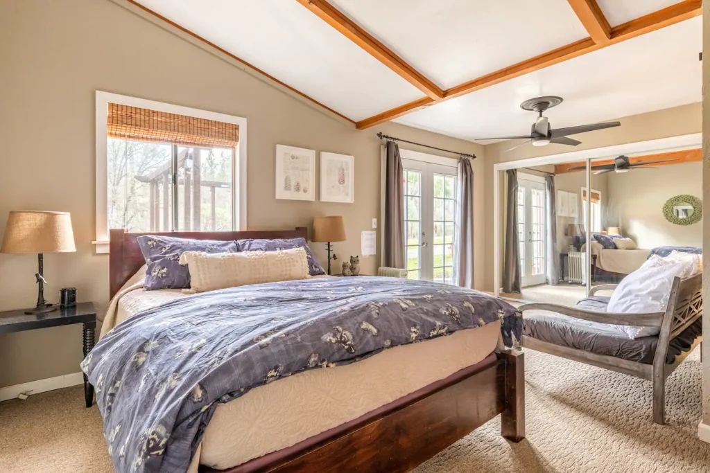 primary bedroom with seating area with queen bed and tall ceilings