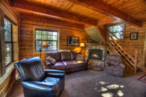 wood paneled living room with stone fireplace and leather couches