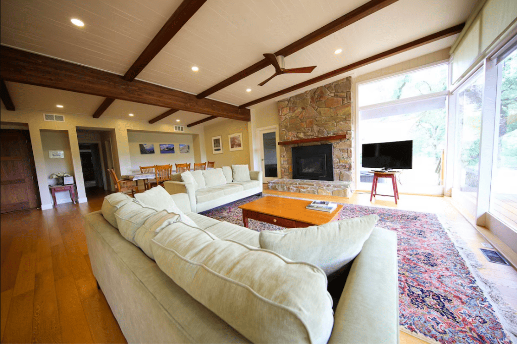 living room with stone fireplace and beams