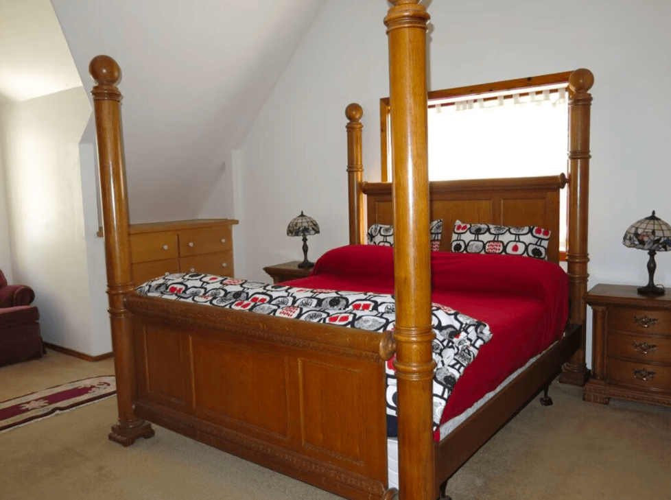 bedroom with four poster queen bed and red bedding