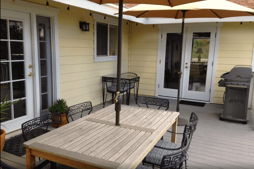 deck with patio table chairs, umbrella, and grill