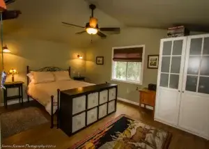 bedroom with window, door, fan. and storage at end of bed