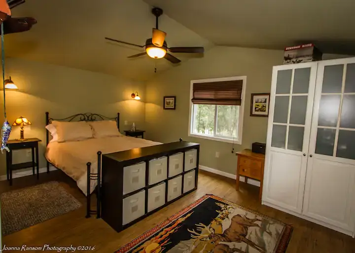 bedroom with window, door, fan. and storage at end of bed