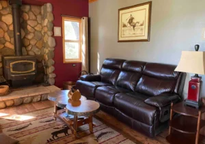 living area with leather couch and stone fireplace