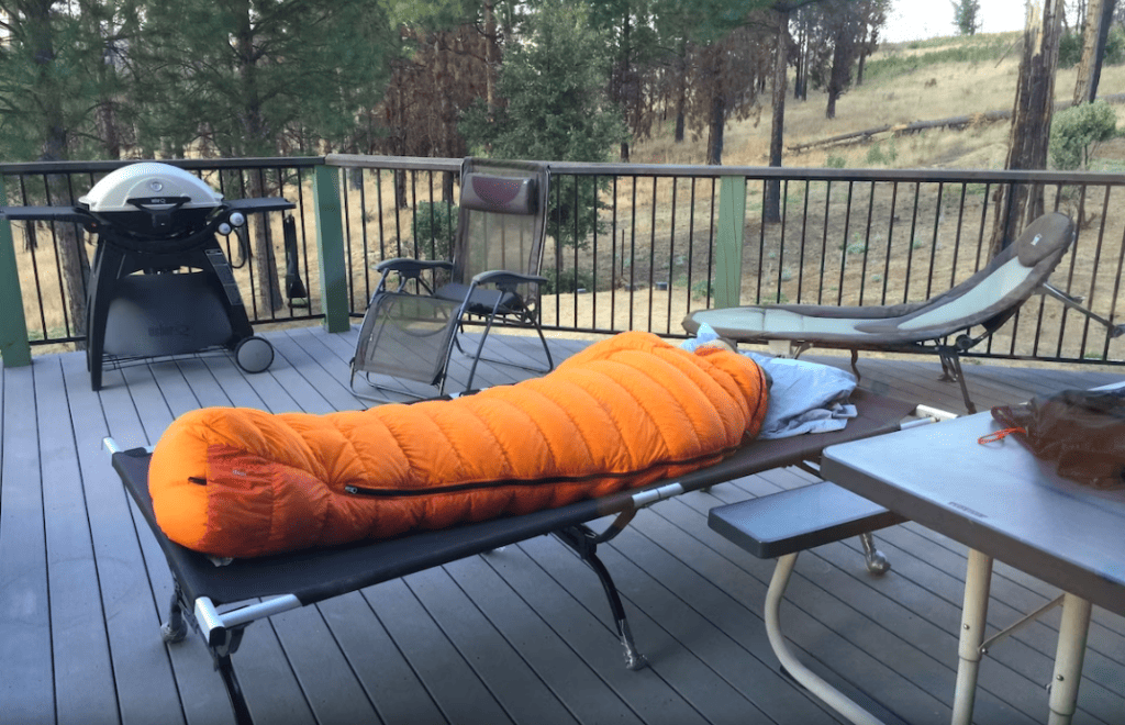 deck with sleeping cot and sleeping bag and outdoor seating and grill