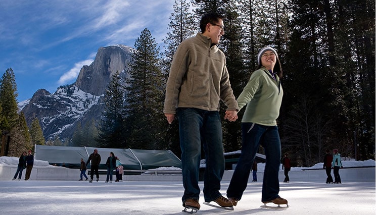 Couple ice skating at Curry Village Ice Rink beneath Half Dome.