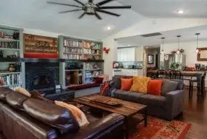 living room with couches, fireplace, bookshelves and fan
