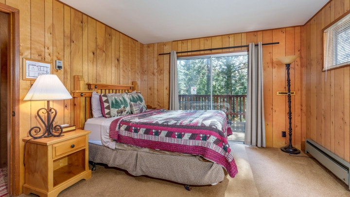 bedroom with red bedding and wood paneled walls