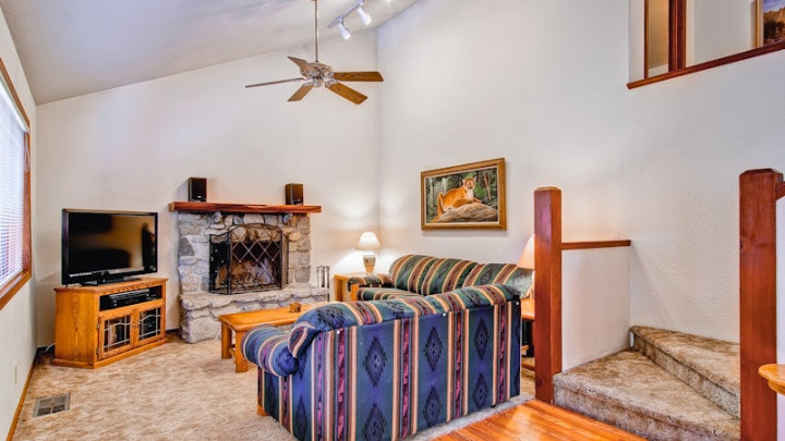 living room with stone fireplace, tall ceilings and striped couches