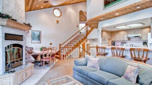 living room with vaulted ceilings, view of stairs, couches, and large fireplace