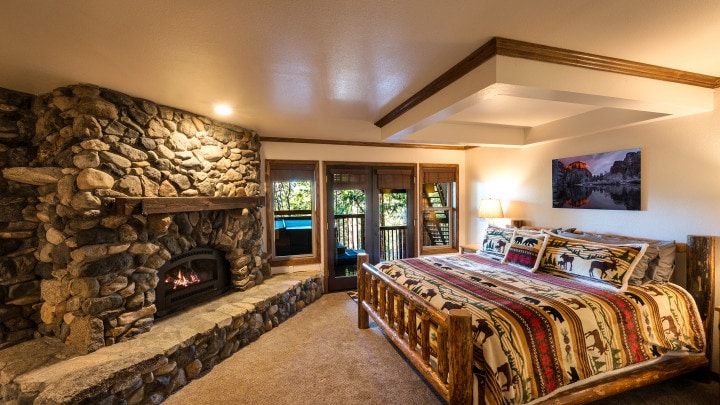 bedroom with stone fireplace and balcony doors