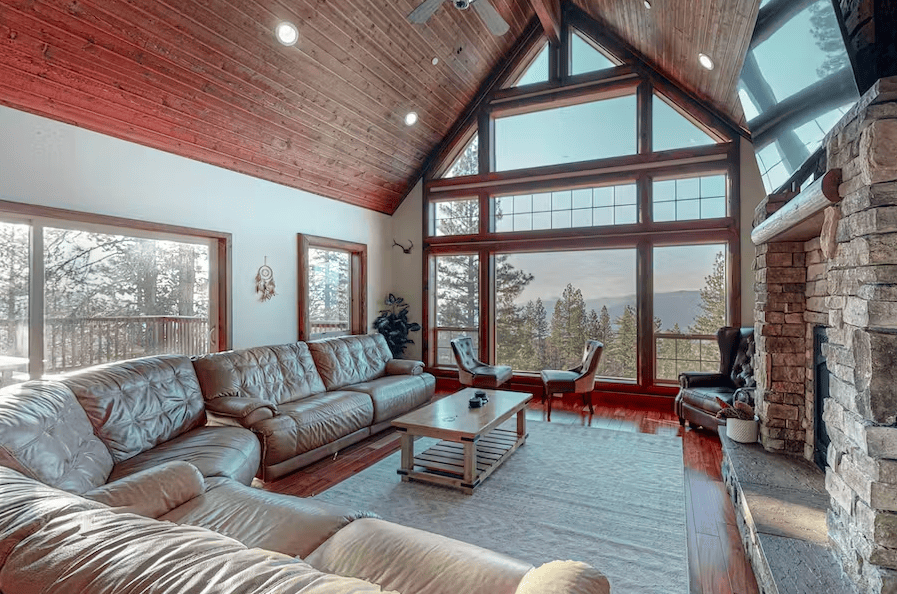 living room with large stone fireplace and cathedral ceilings with wall of windows