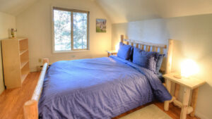 bedroom with blue bedding and wood carved bed frame and window