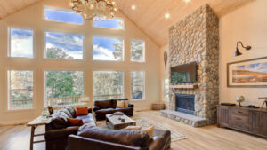 living room with large windows and vaulted ceilings. stone fireplace and television