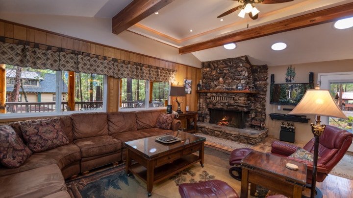 living area with stone fireplace, couches and beams
