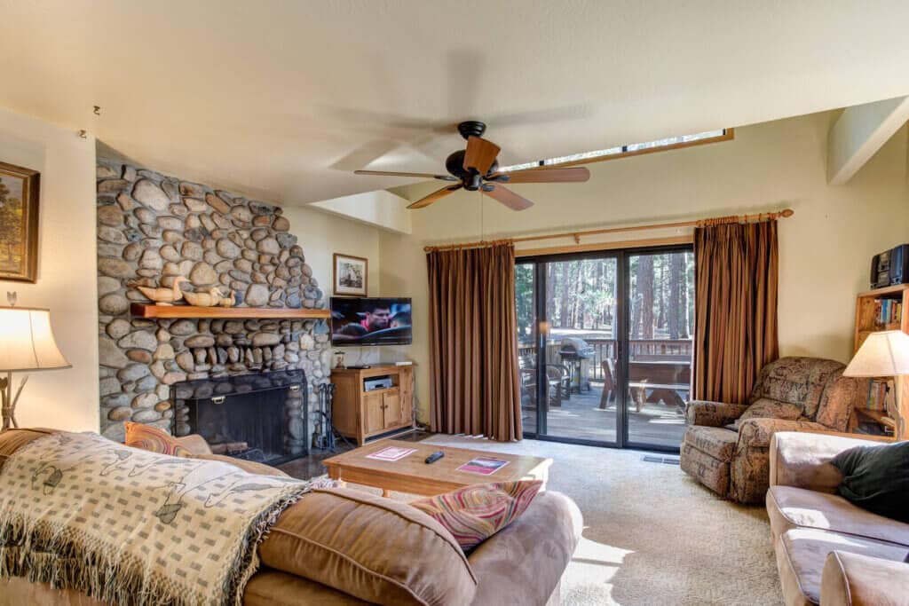 living room with vaulted ceiling and stone fireplace