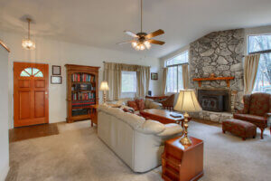 living room with tall ceilings, stone fireplace and couches