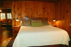 bedroom with white bedding and wood paneled walls