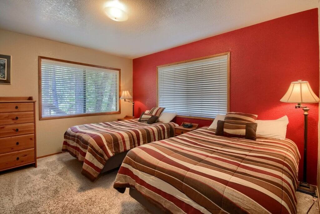 bedroom with red accent wall and two beds with striped bedding
