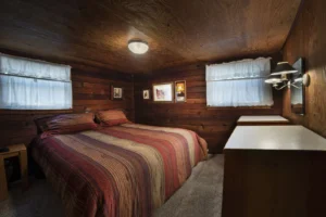 bedroom with low wood ceilings and striped bedspread