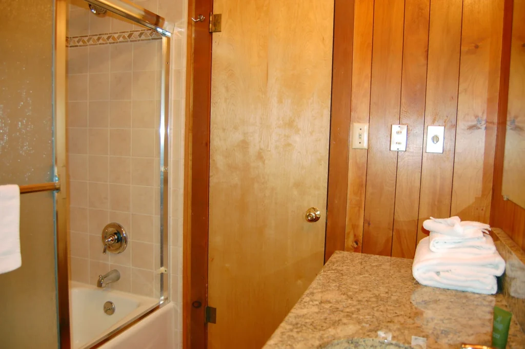 wood paneled bathroom with shower bath combo