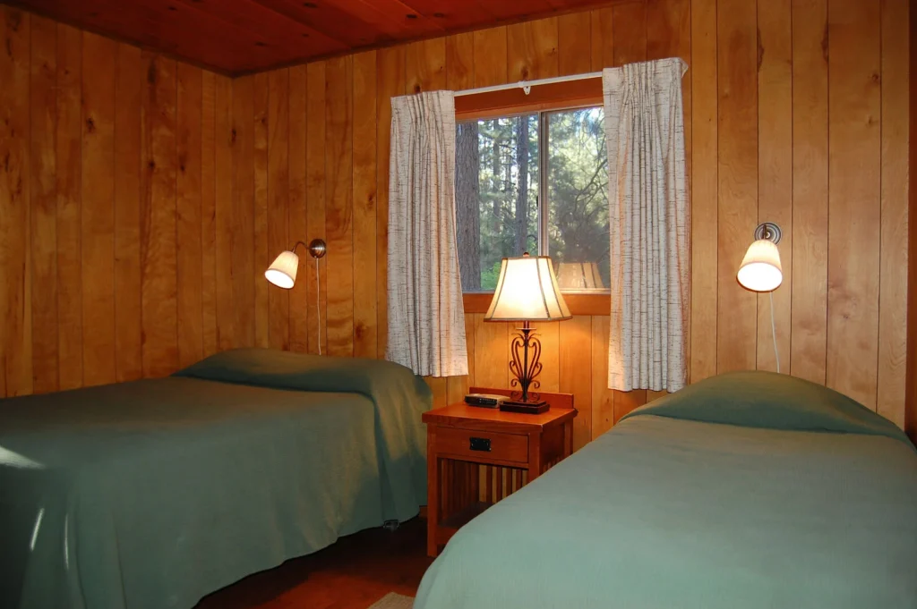 two beds with green bedding and window