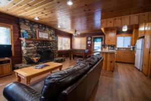 living room with leather couch, stone fireplace, and foosball table