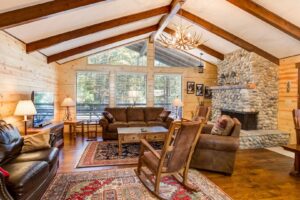 living room with beamed ceilings and couches and stone fireplace