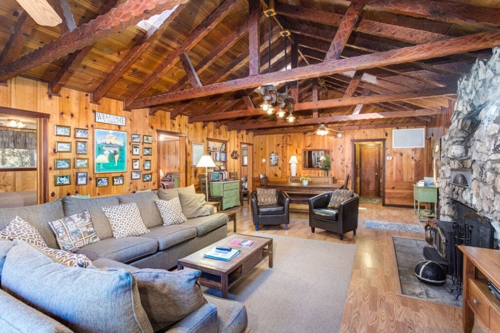living area with couches, stone fireplace and beams