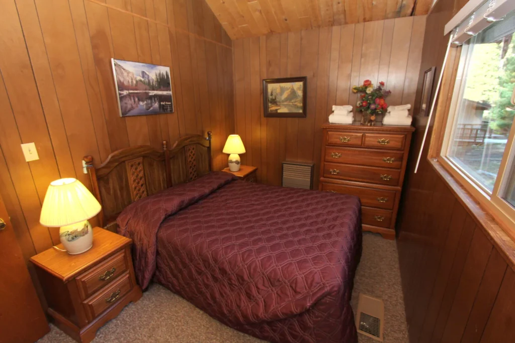 bedroom with wood walls and ceiling, deep red bedspread