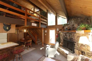 living area with loft, beams and stone fireplace