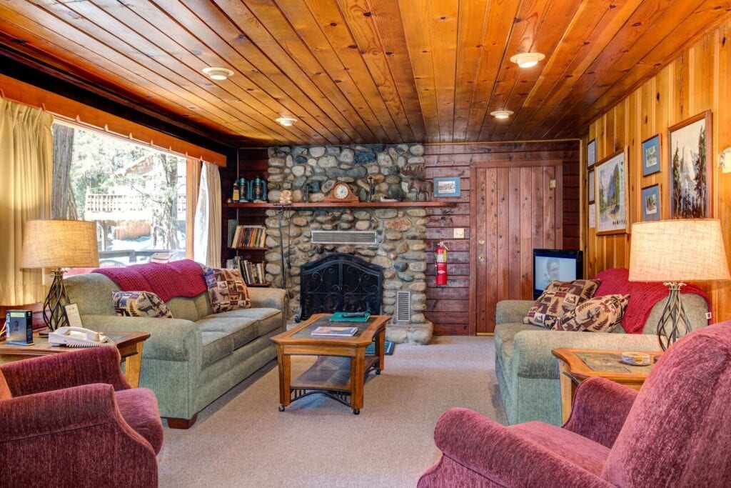 living room with wood paneled ceilings and stone fireplace, seating