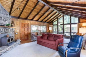 living room with tall ceilings and beams, stone fireplace and seating