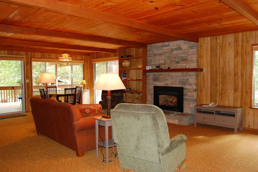 living room with wood ceiling, stone fireplace, and seating