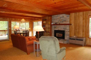 living room with wood ceiling, stone fireplace, and seating