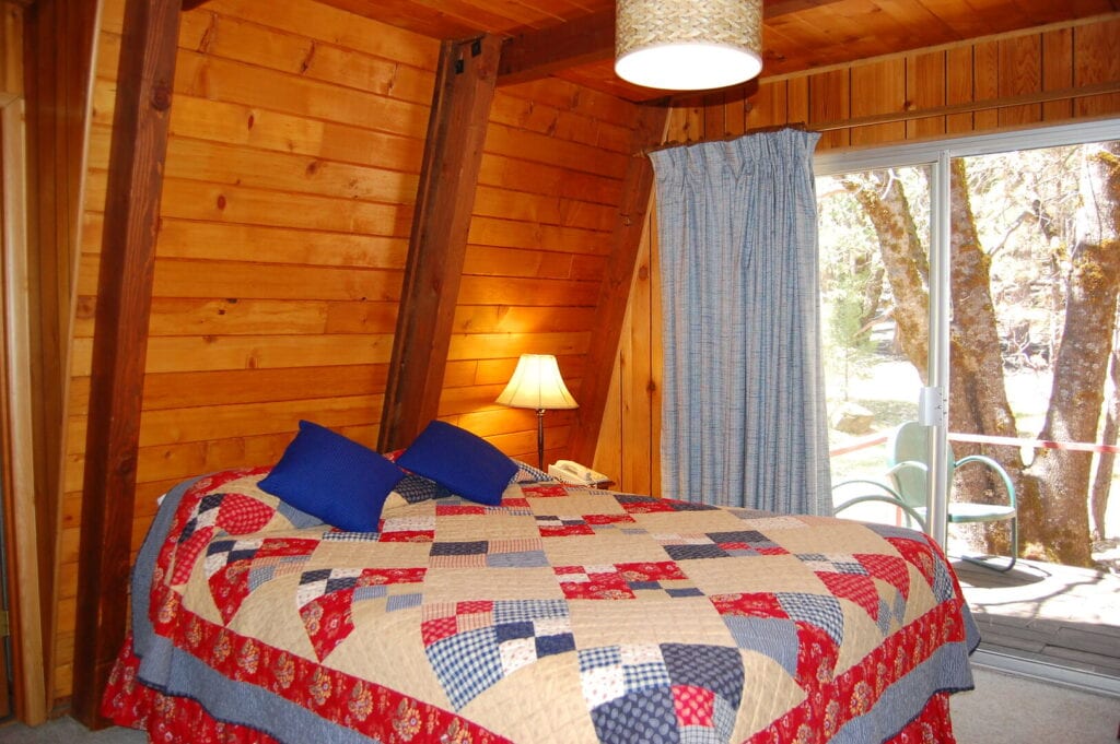 bedroom with wood walls and beams. with sliding doors to deck