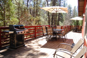 deck with grill, and two umbrella tables with chairs