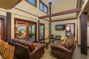 living room with vaulted ceilings, beams, leather couches and wood stove