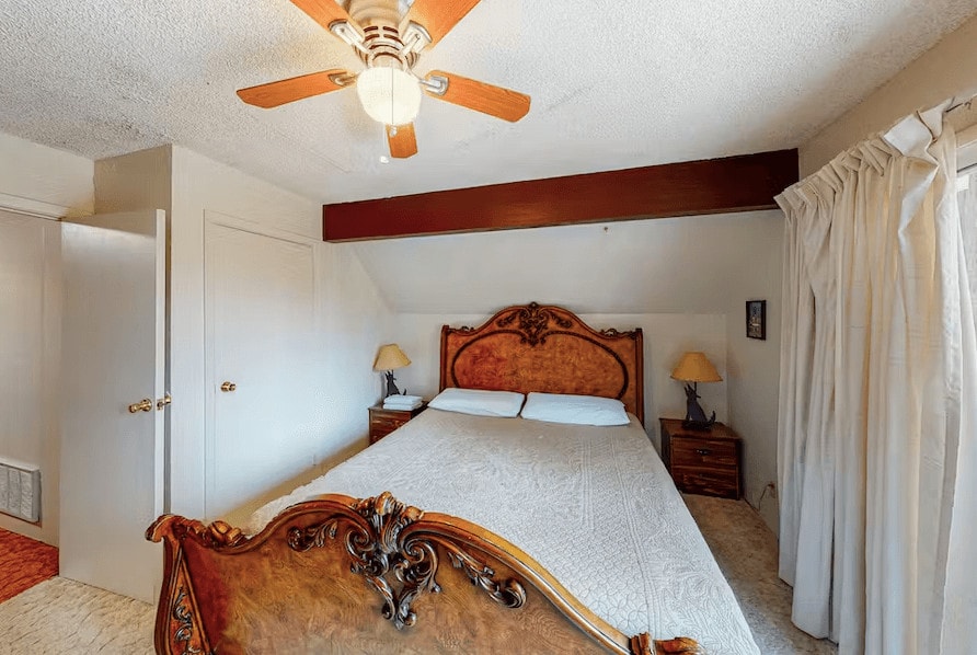 bedroom with wood bed, beams, and ceiling fan
