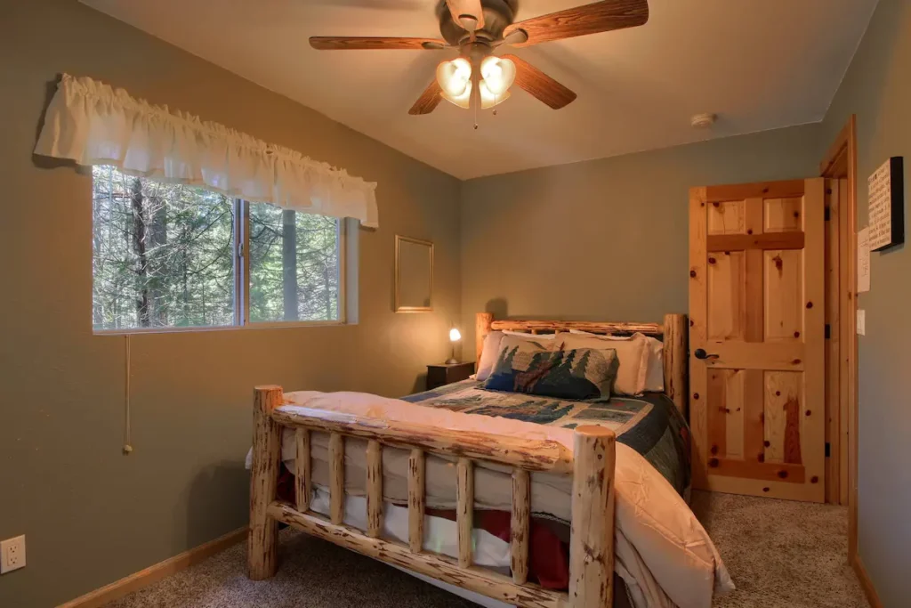 bedroom with wood carved bed, ceiling fan, and window