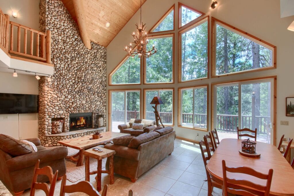 living room with tall ceilings, big windows, and stone fireplace