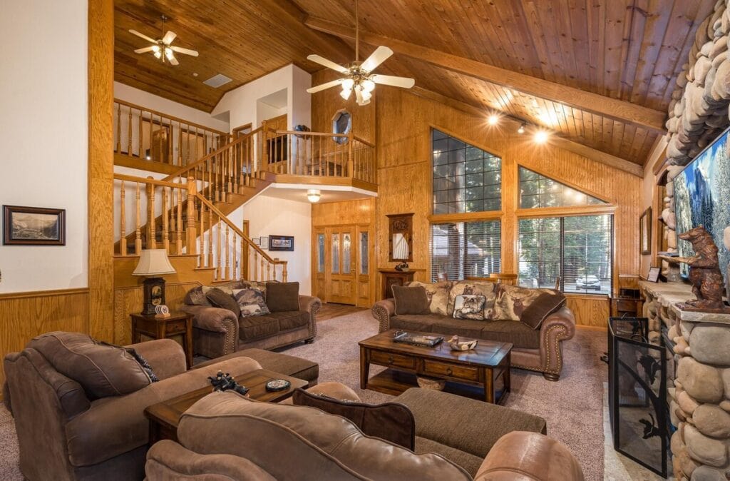 living room with vaulted ceilings, couches, stone fireplace, and television.