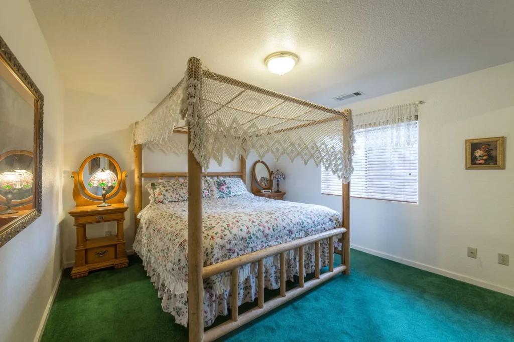 bedroom with green carpet and canopy bed
