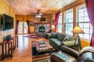 living room with couches, chairs, stone fireplace and television