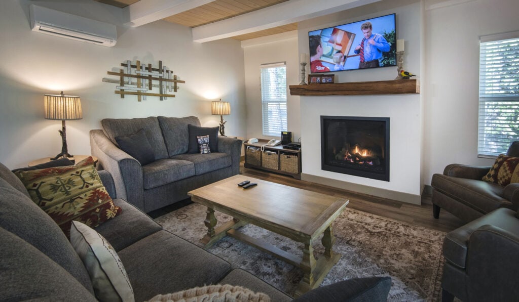 living room with couch, fireplace, and beams with couches