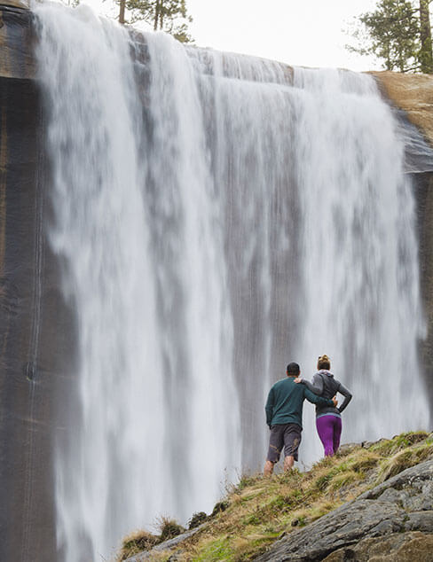 couple standing in front of waterfall