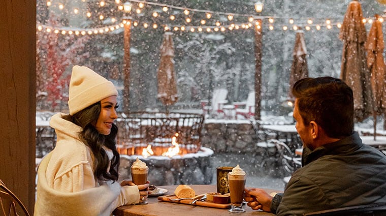 Couple enjoying hot drinks while admiring the winter scenery at Jackalopes Bar and Grill at Tenaya at Yosemite