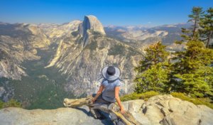 Woman sitting at Glacier Point looking at Half Dome