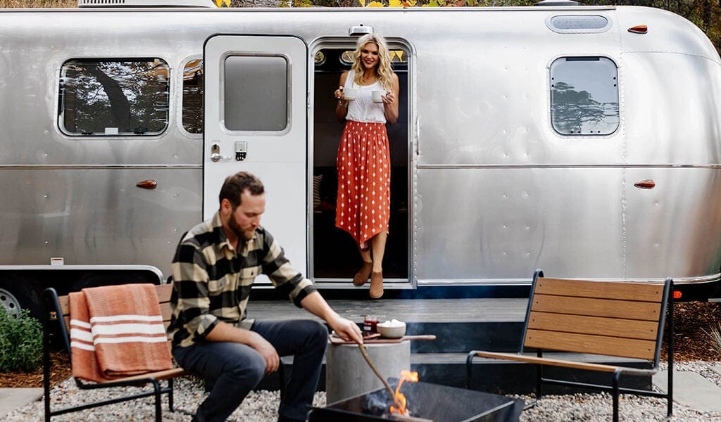 Couple outside their rented Airstream Trailer at AutoCamp Yosemite